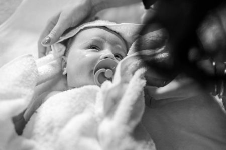 Bebelus uitandu-se la mama, dupa ce a iesit din cristelnita, surprin de fotograf botez in Bucuresti.