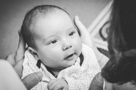 Fotograf botez Bucuresti, bebelus tinut pe genunchi, cu privirea la mama