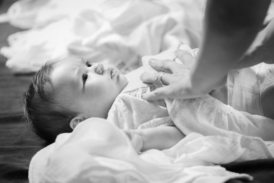 Bebelusul in biserica este dezbracat de mama pentru scufundarea in cristelnita, cadru surprins de fotograf botez in Bucuresti