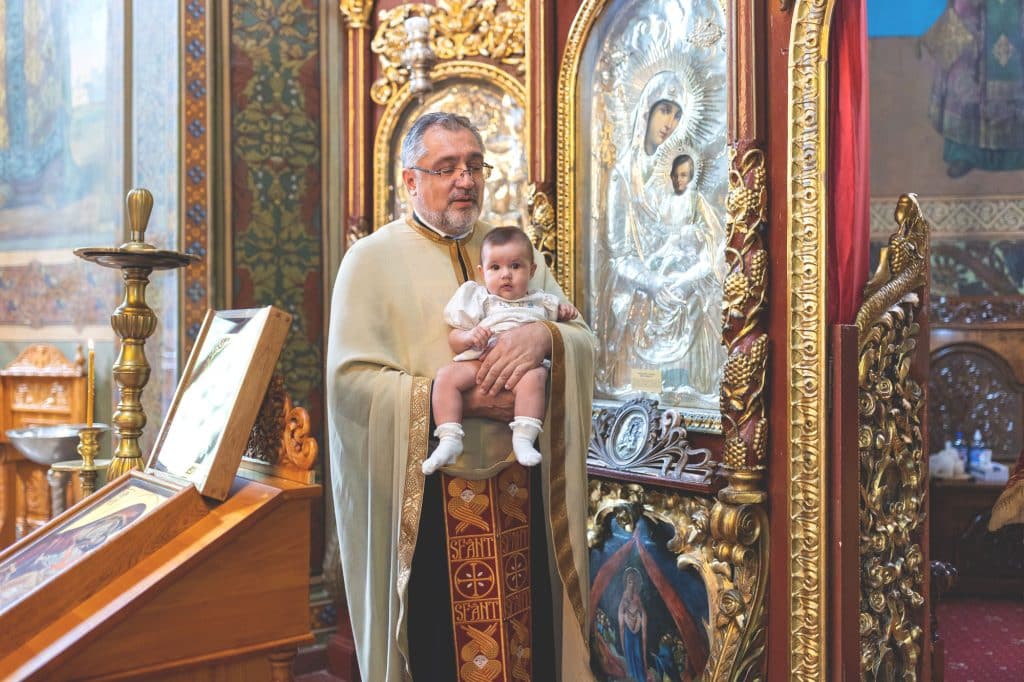 Fotograf botez Bucuresti: preotul care tine fetita in dreptul Usilor Imparatesti la intrarea in altar