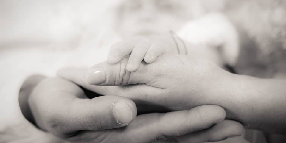 Fotograf botez Bucuresti, mana bebelusului in mainile parintilor