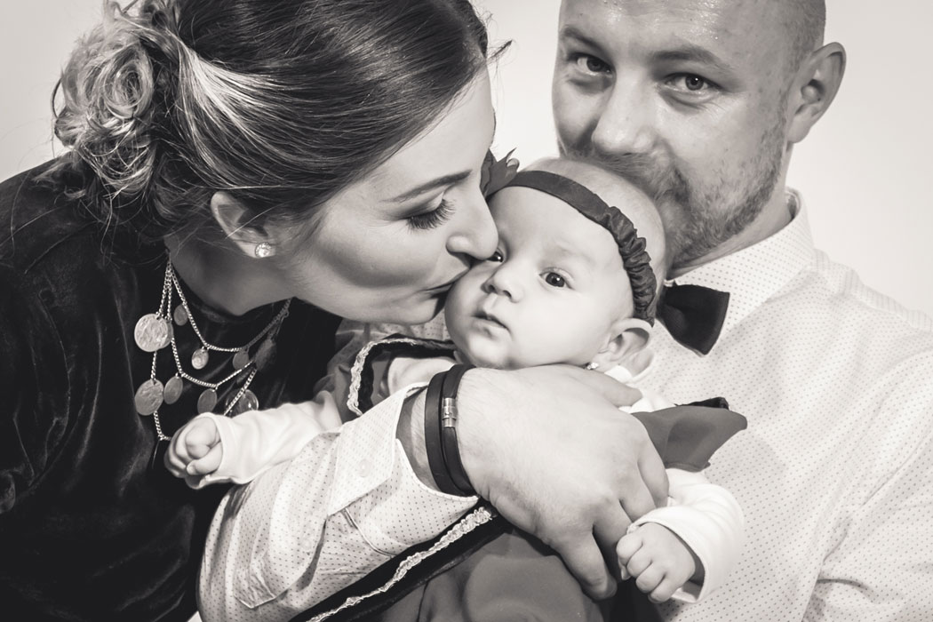 Tatal tine copilul in brate si mama il saruta pe obraz. Fotograf Botez Bucuresti.